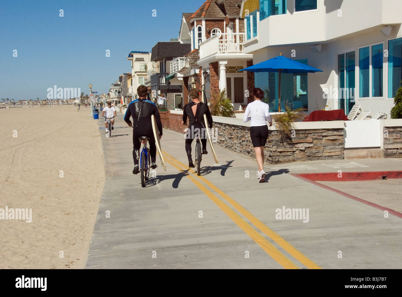 Surfers on bikes, runner,  balboa peninsula newport beach, orange county, california, ca usa three miles 5 km long, california Stock Photo