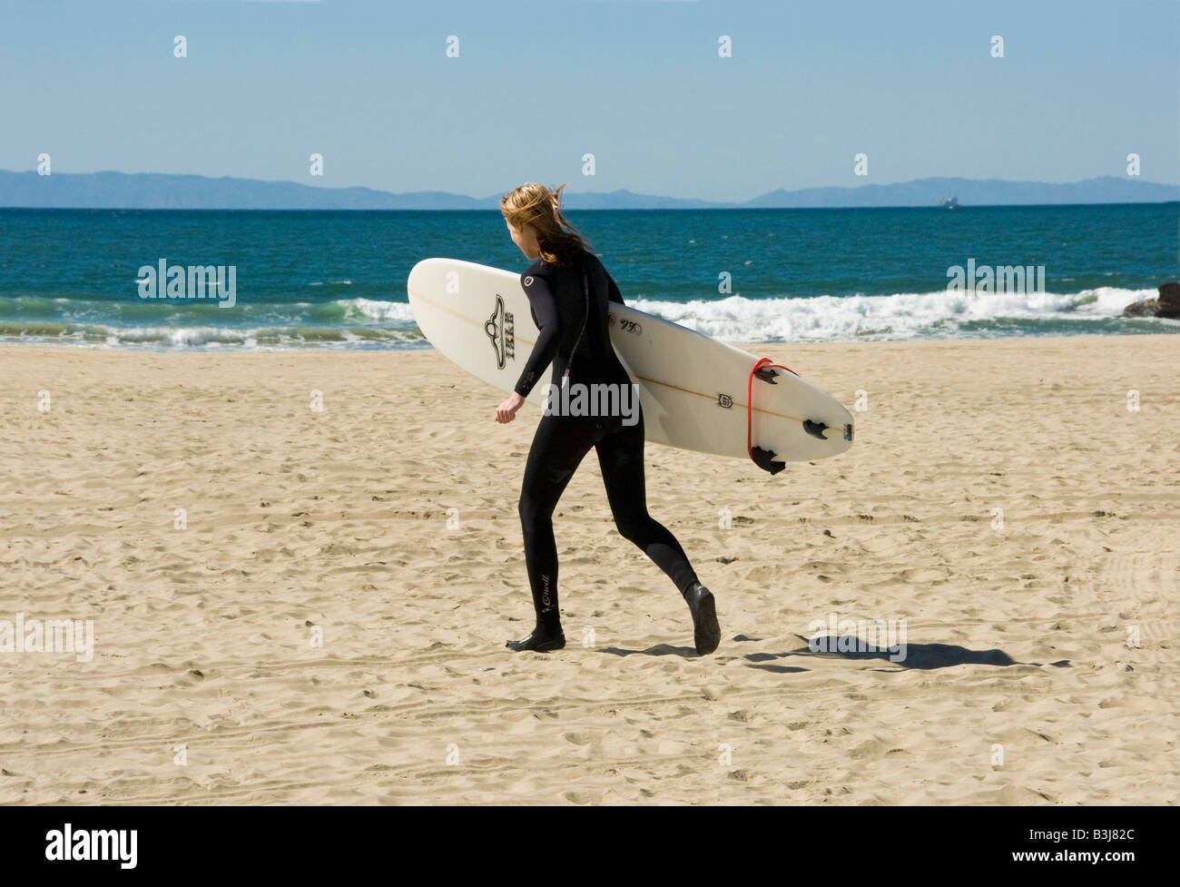 balboa peninsula surfer female woman 20's running newport beach orange county, california, ca usa three miles 5 km long, ca Stock Photo