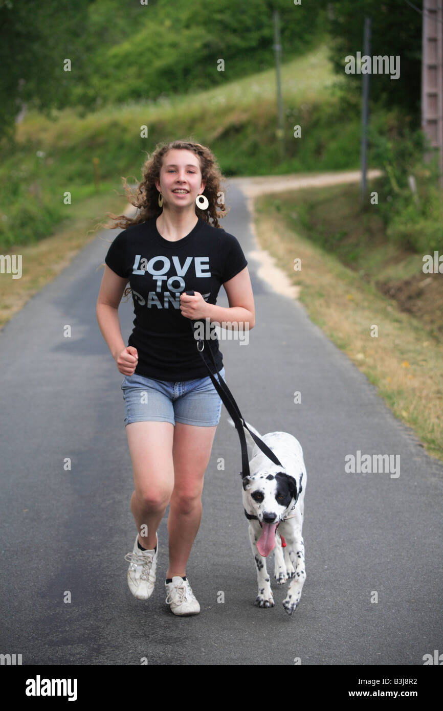 girl running with black and white spotty dog Stock Photo