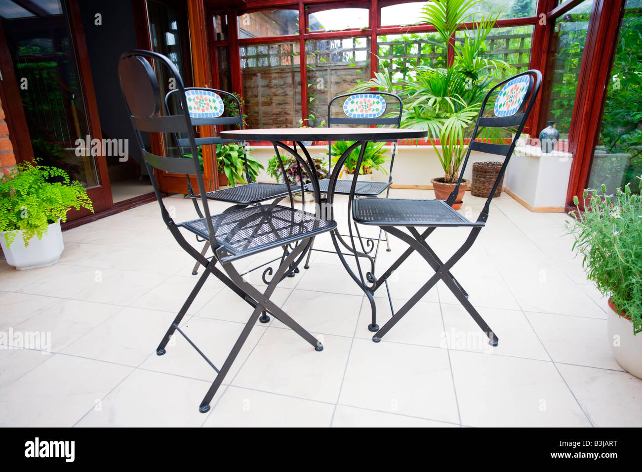conservatory tables chairs plants room in house next to garden Stock