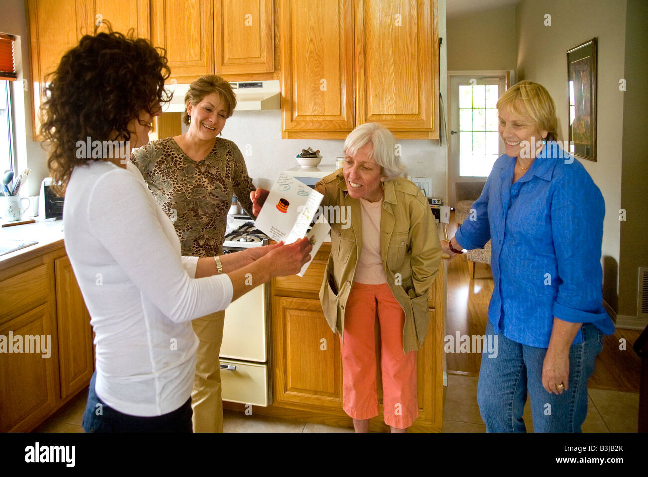 A 50 year old woman smiles happily while holding a Fifty and Fantastic doll joke gift at her birthday party in Mission Viejo Cal Stock Photo