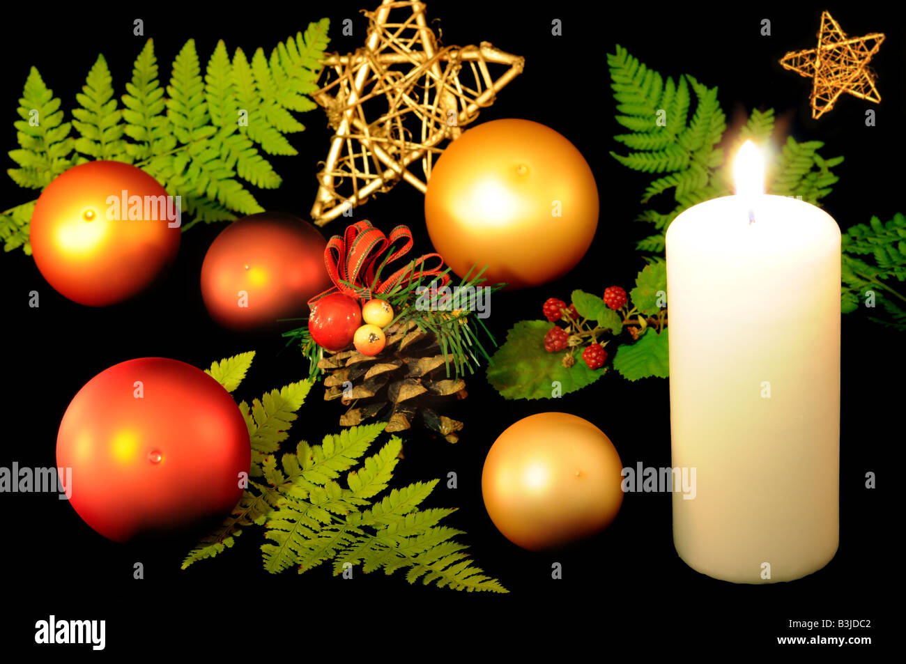 Christmas still life with decorative balls, fern, cone and burning candle. Stock Photo