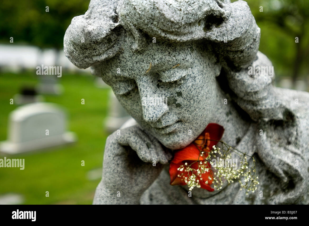 A carved woman in a cemetery with a red rose Stock Photo