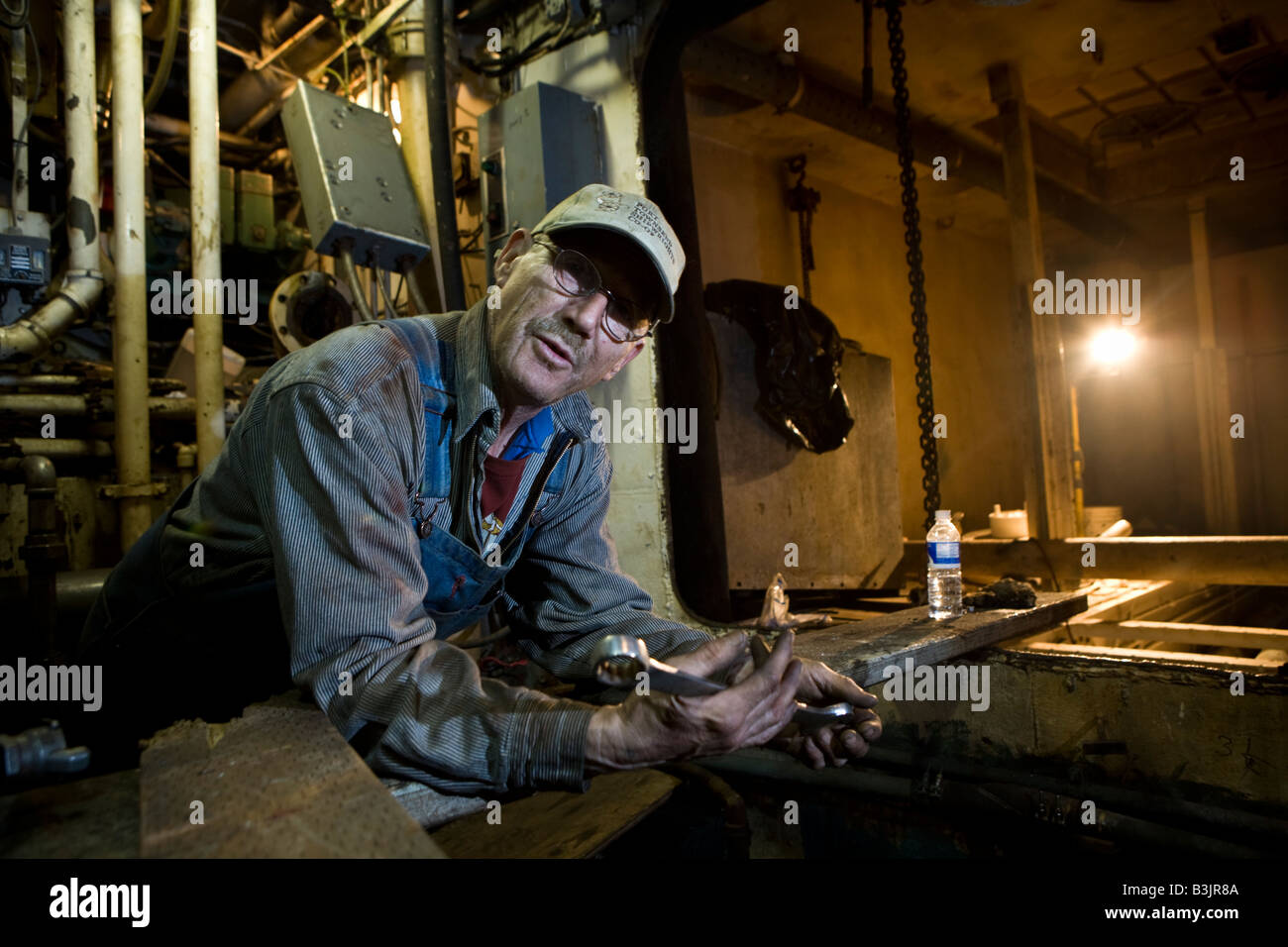 Milton Bud Altom a welder at the shipyard in Port Townsend checks the engine room of the fishing boat Anna Marie Stock Photo