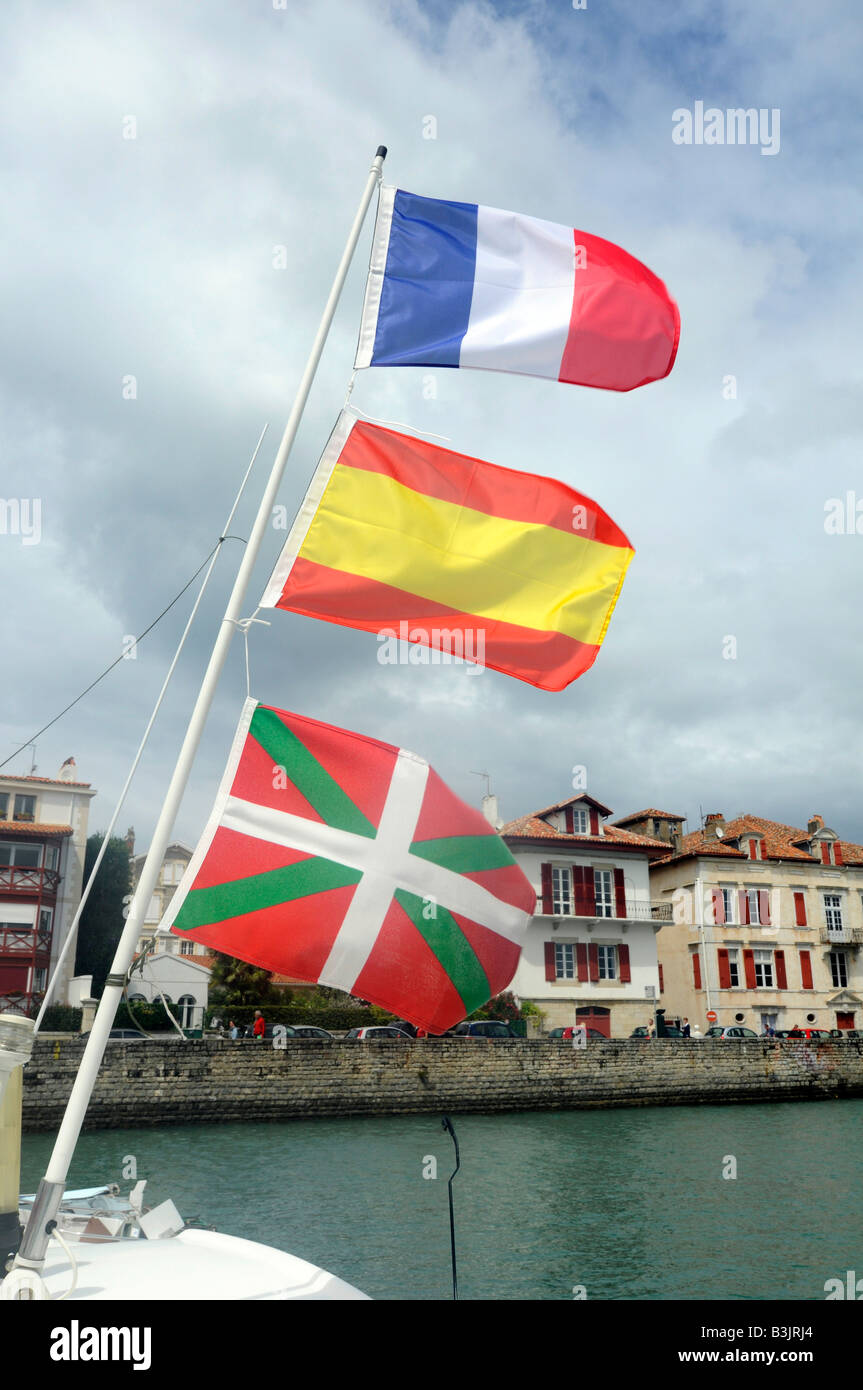 Three flags flying from a boat's mast, from bottom to top: Basque flag, Spanish flag, French flag, in St Jean de Luz, France Stock Photo