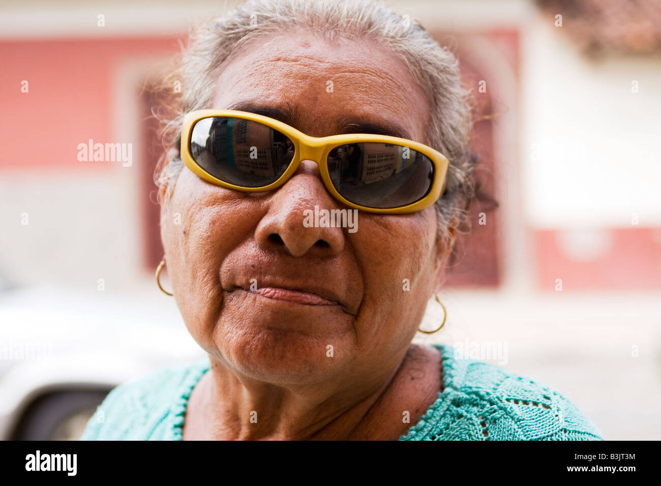 A woman walking through Granada, Nicaragua wearing a fashionable pair of colored sunglasses Stock Photo