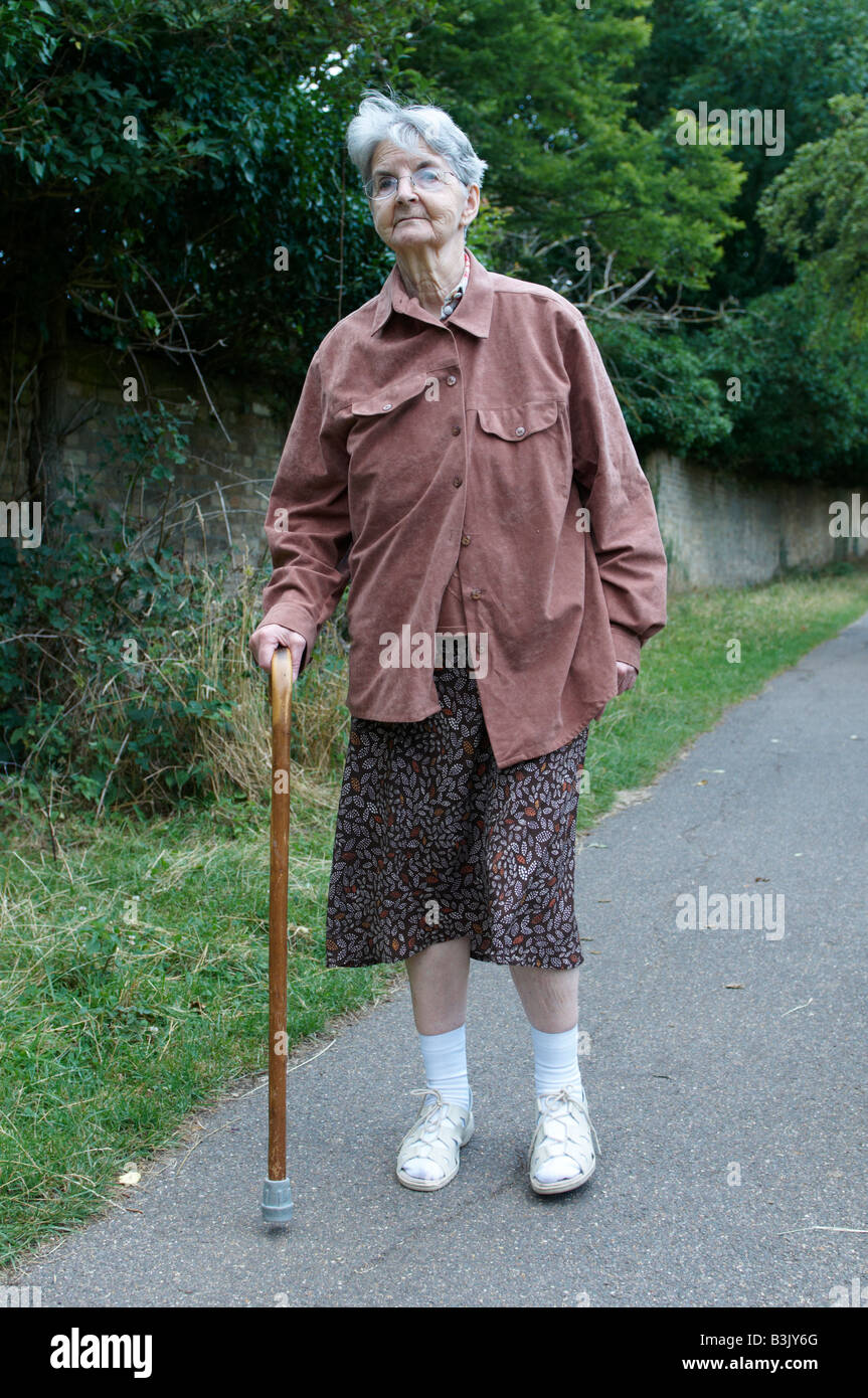 Elderly woman (stroke sufferer) walking with stick Coe Fen Cambridge Stock Photo