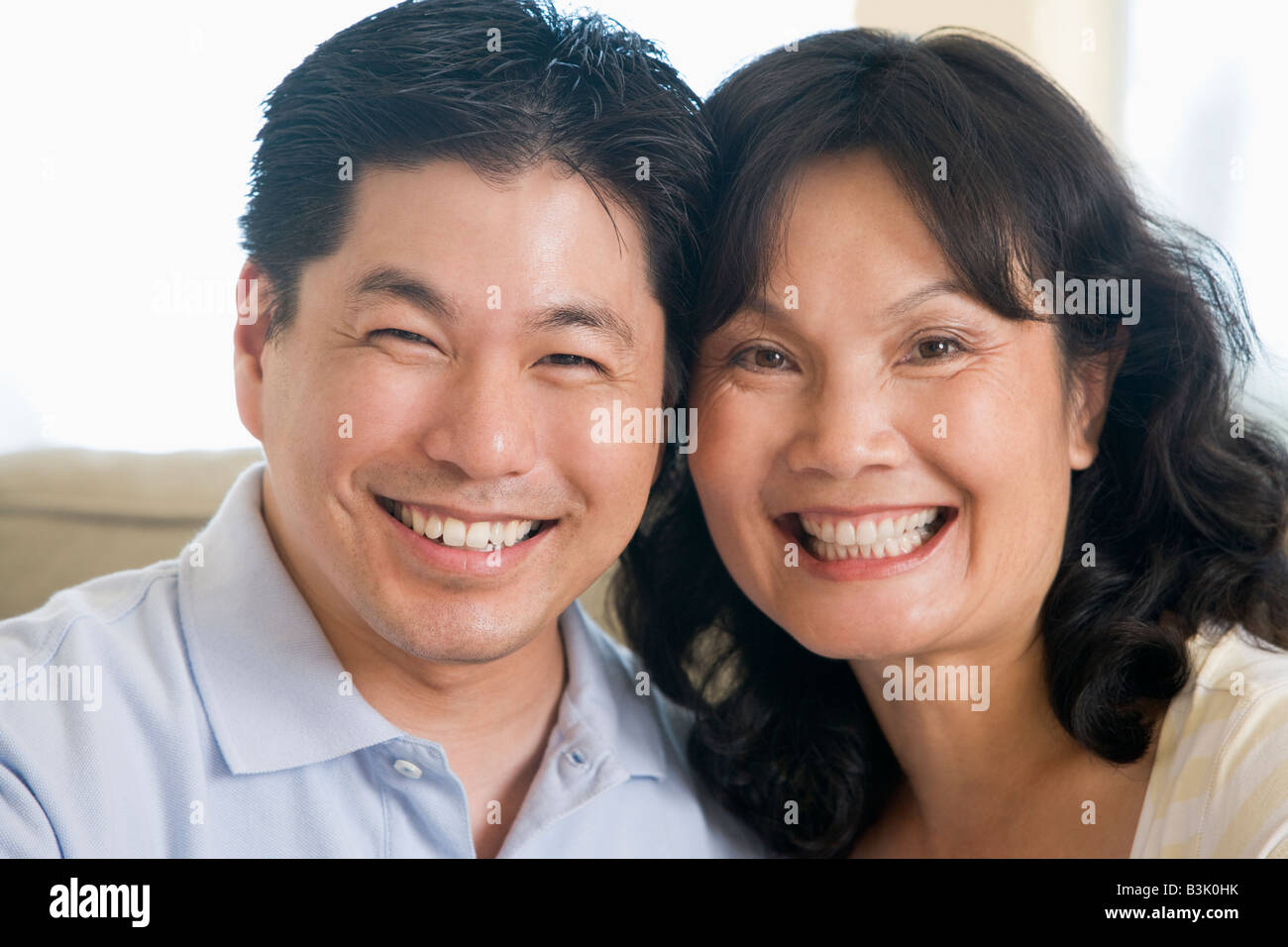 Couple relaxing in living room and smiling Stock Photo - Alamy