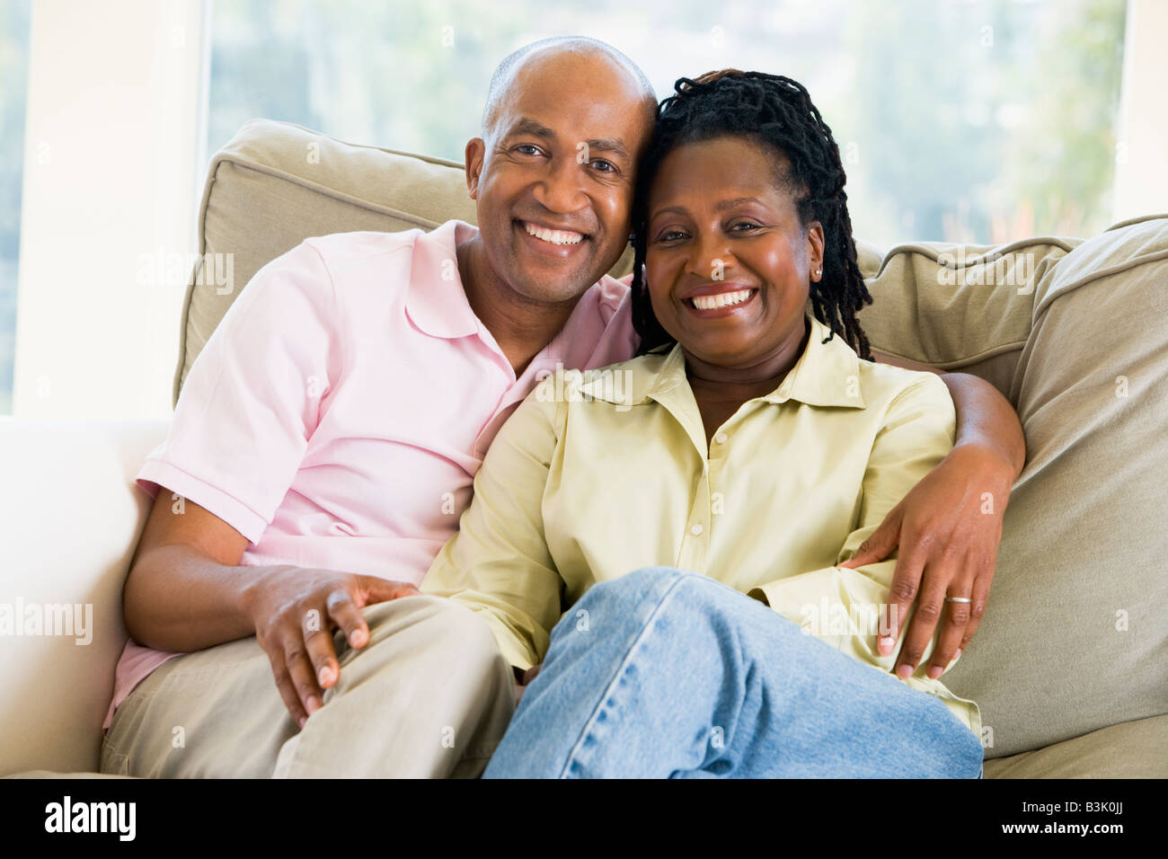 Couple relaxing in living room and smiling Stock Photo - Alamy
