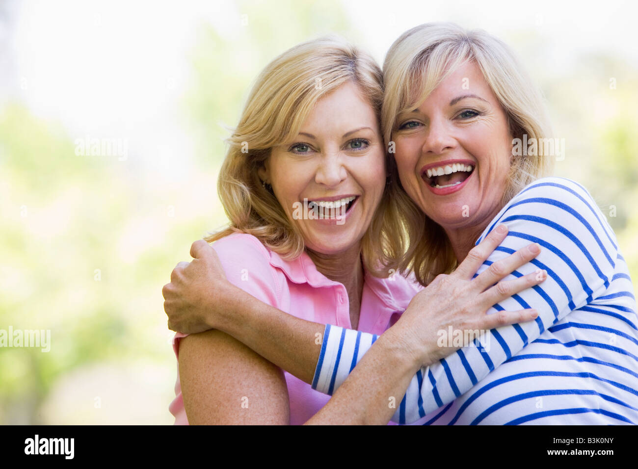 Two women outdoors hugging and smiling Stock Photo - Alamy