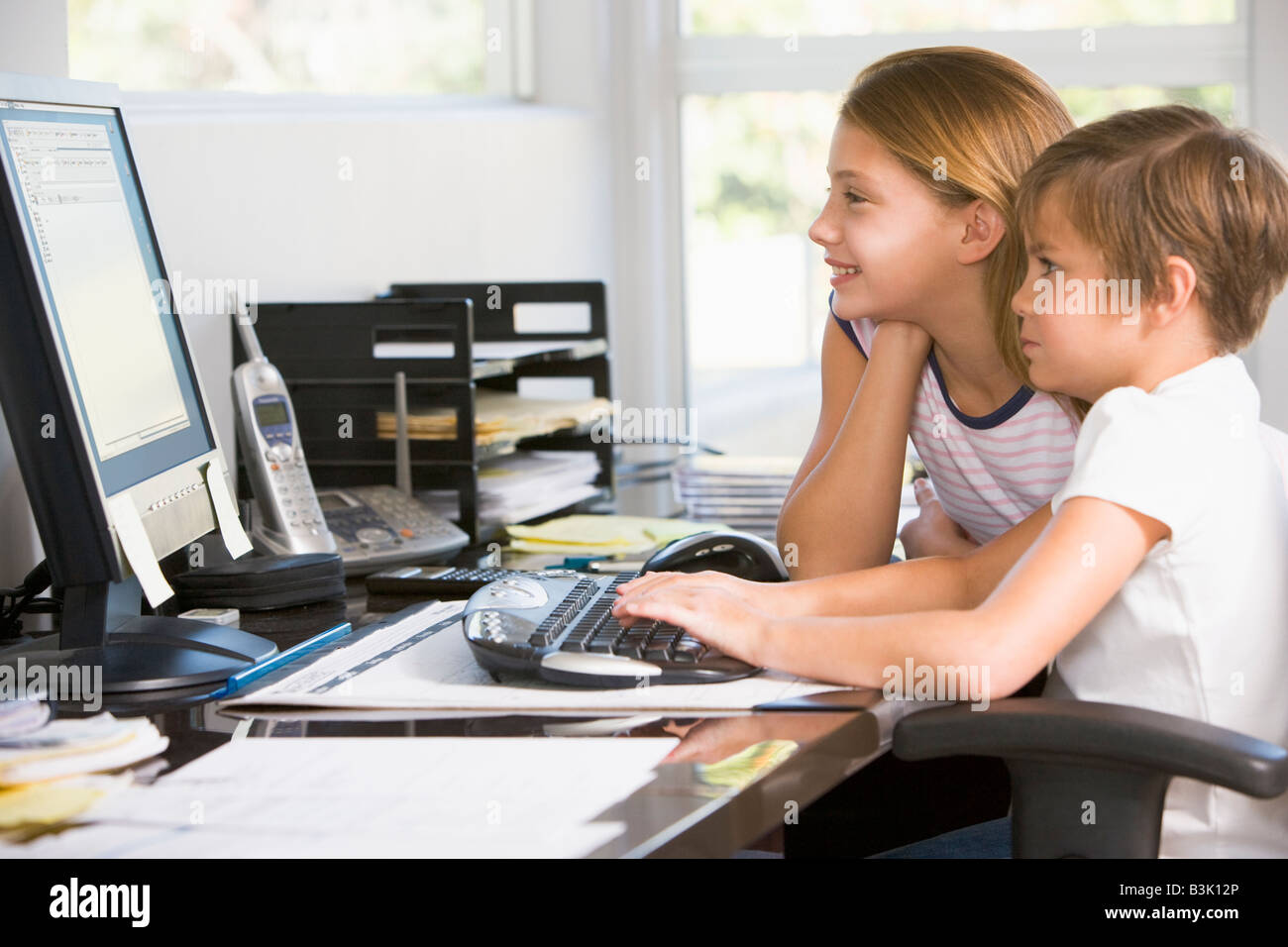 Young boy and young girl in home office with computer smiling Stock ...