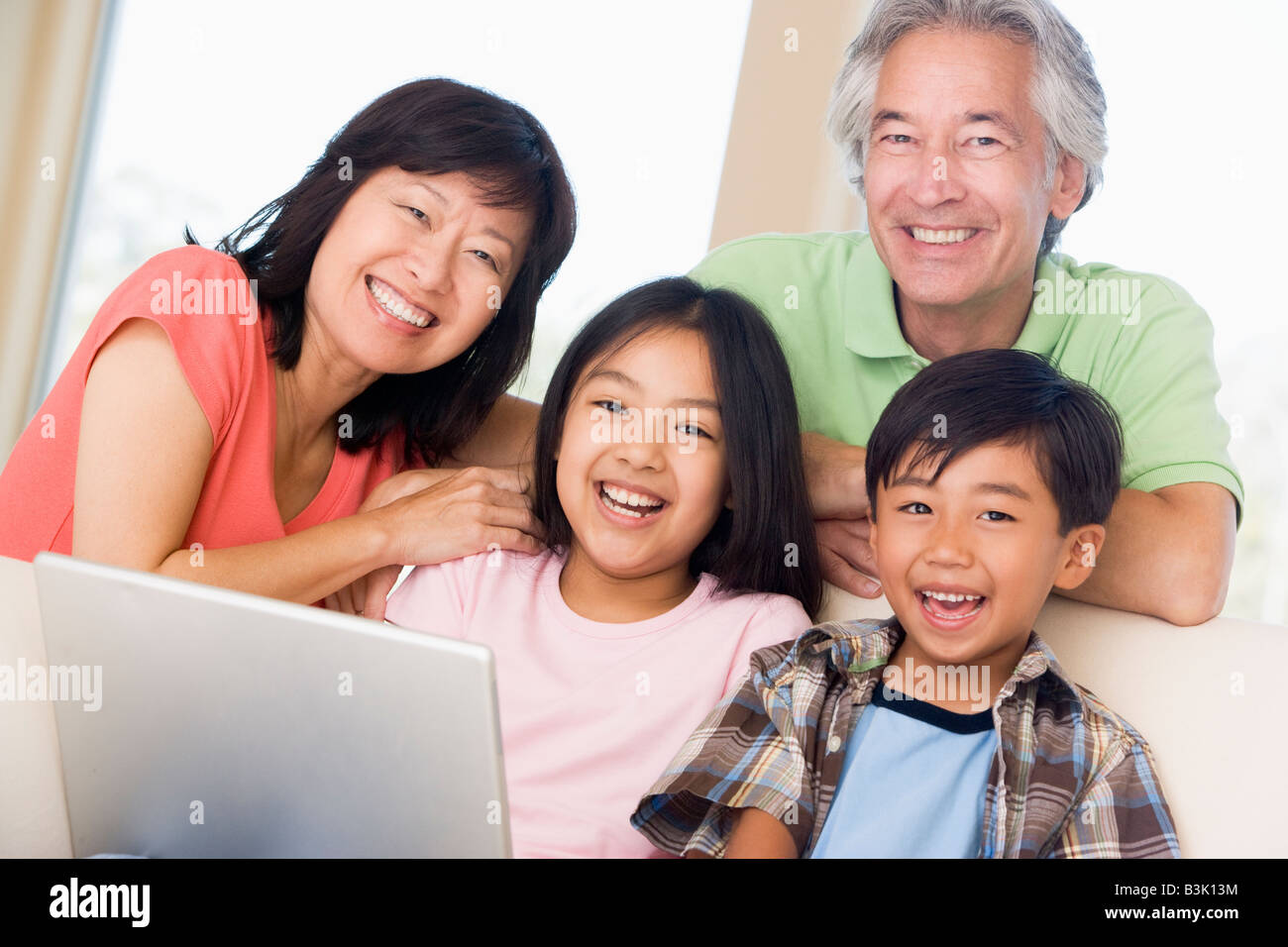 Couple with two young children in living room with laptop smiling Stock ...