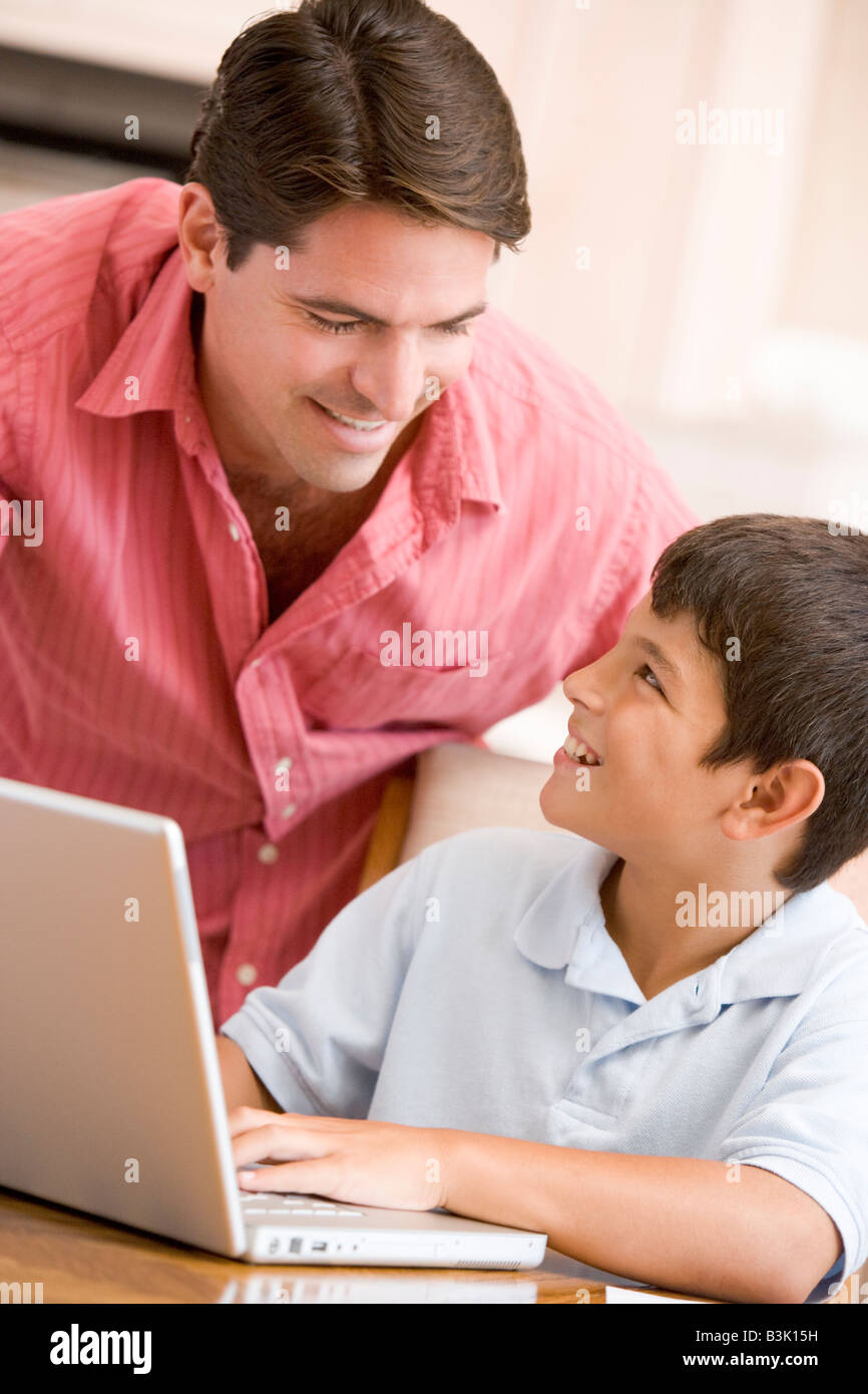 Man helping young boy in kitchen with laptop smiling Stock Photo - Alamy