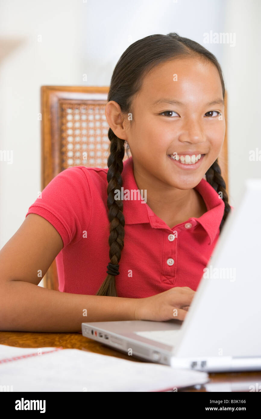 Young girl with laptop in dining room smiling Stock Photo - Alamy