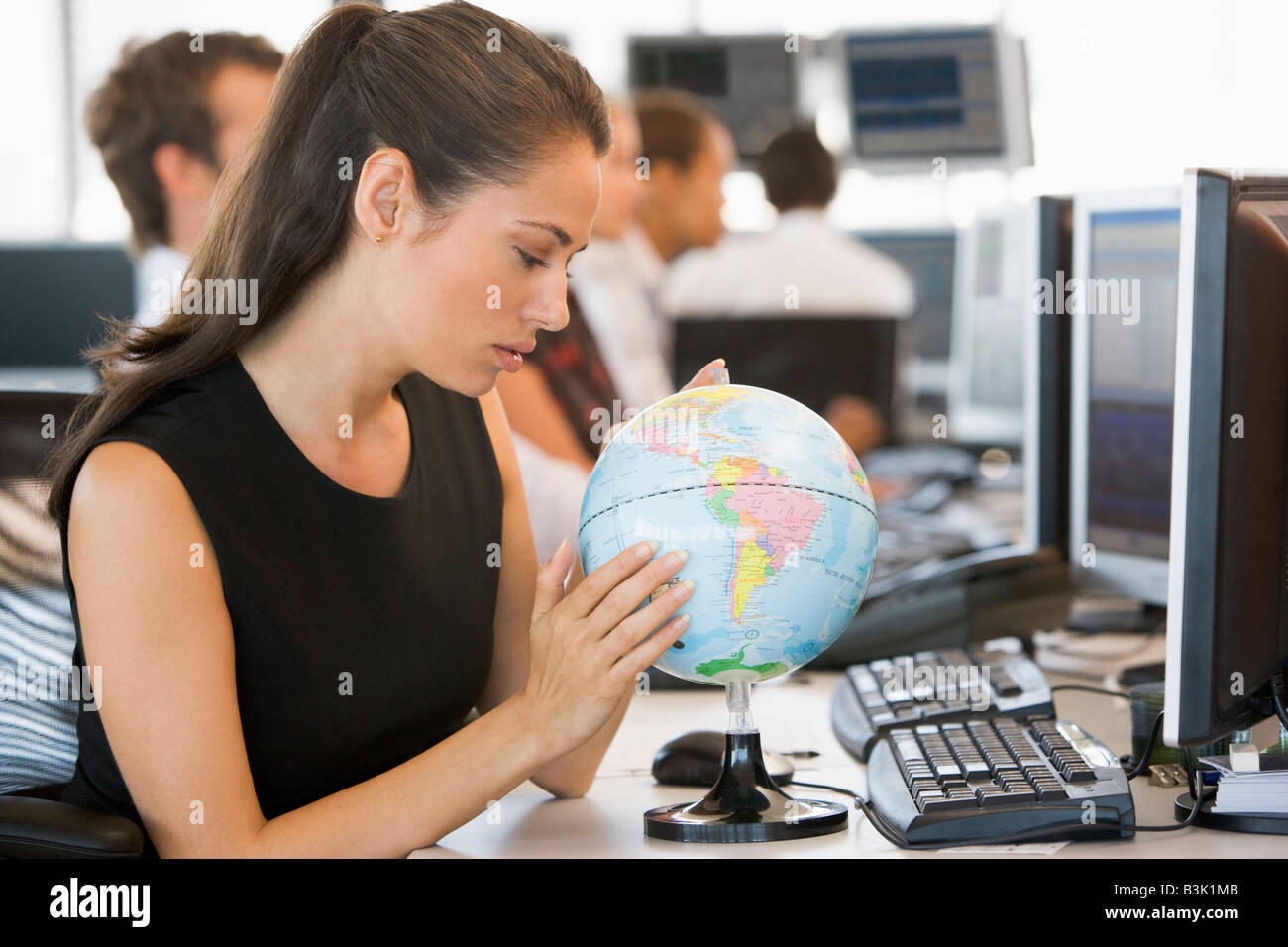 Businesswoman in office space with desk globe Stock Photo