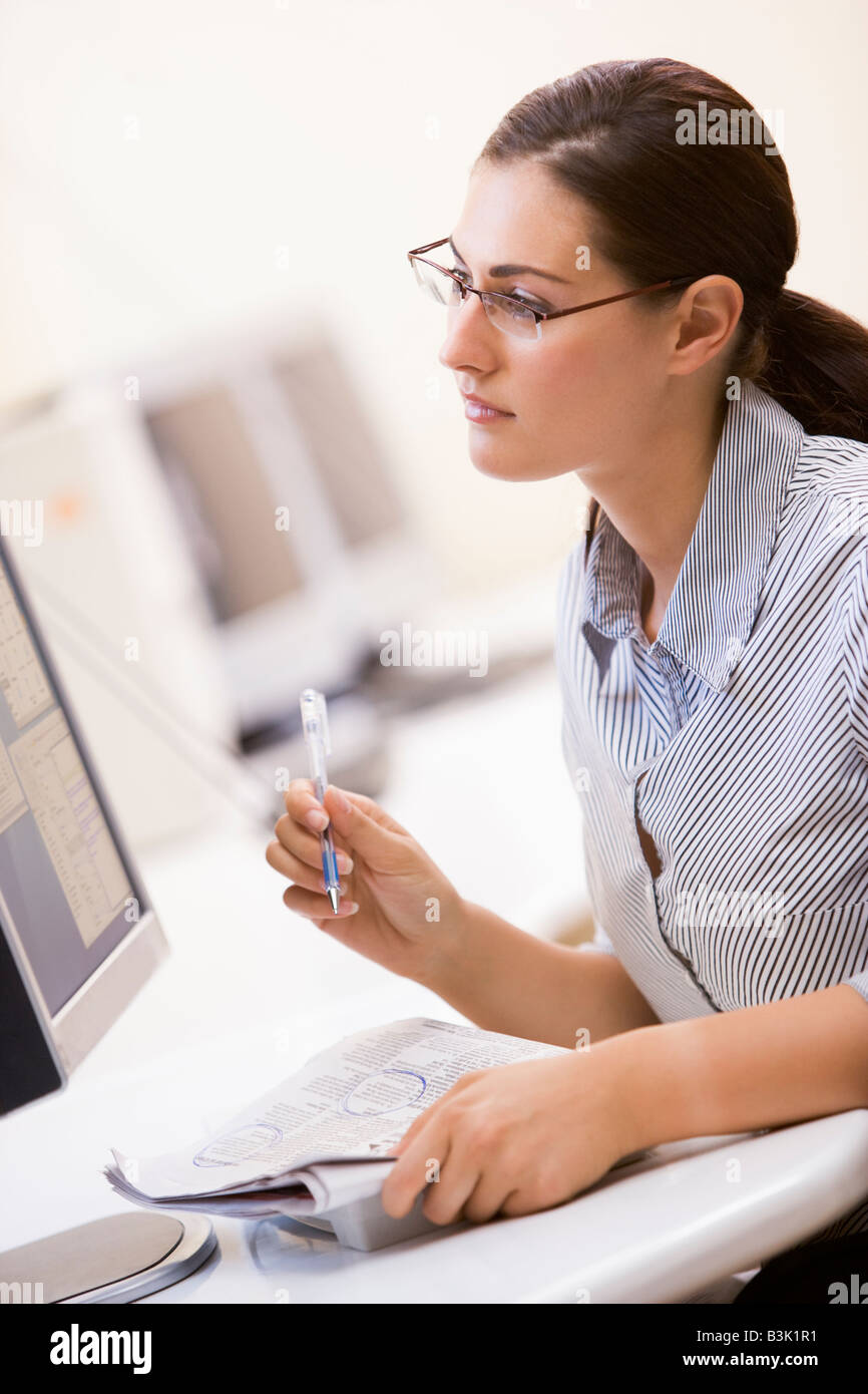 Woman in computer room circling items in a newspaper Stock Photo