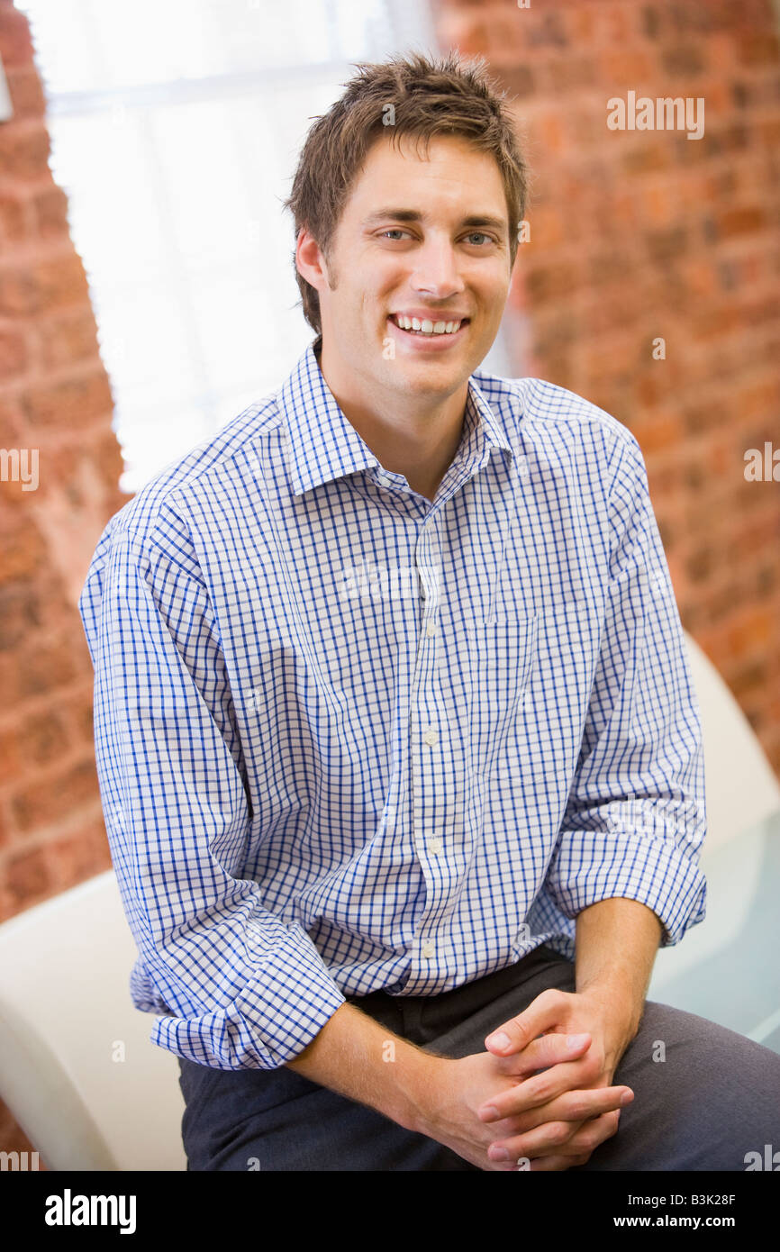 Businessman sitting in office space smiling Stock Photo - Alamy