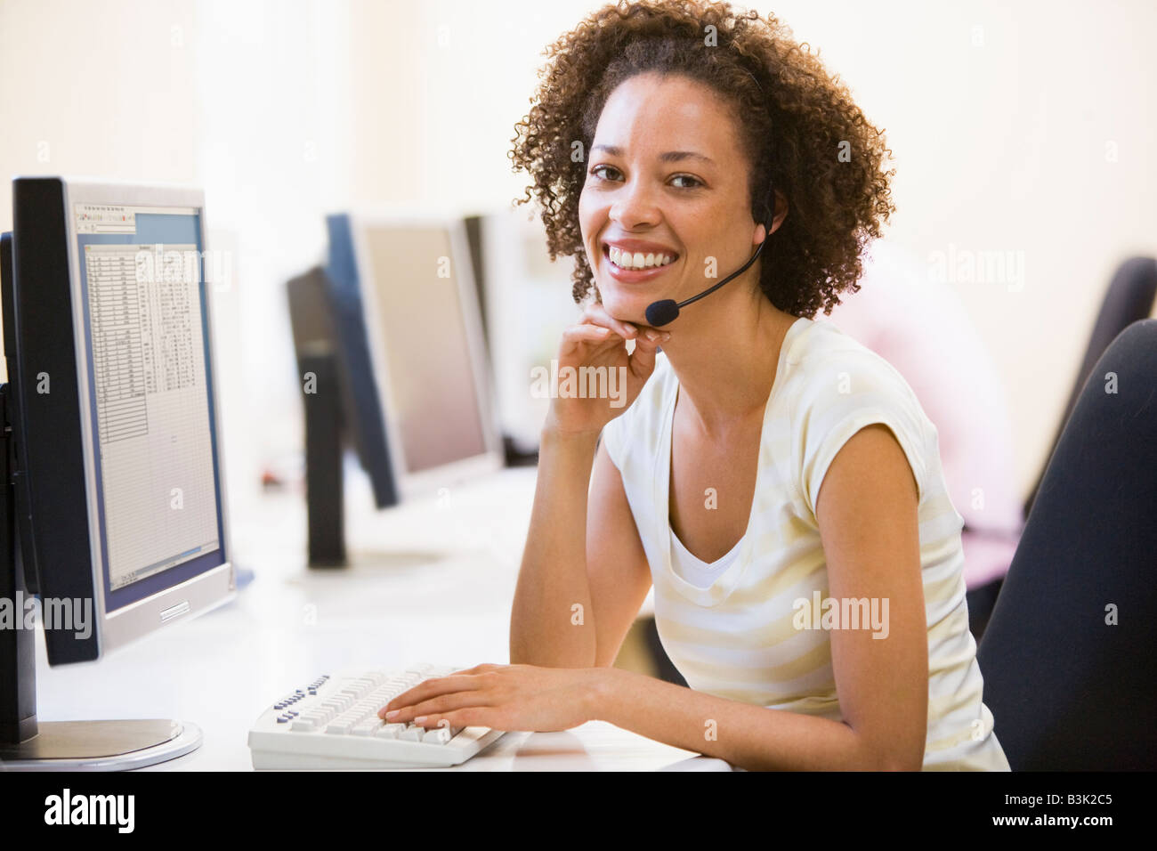 Woman wearing headset in computer room smiling Stock Photo