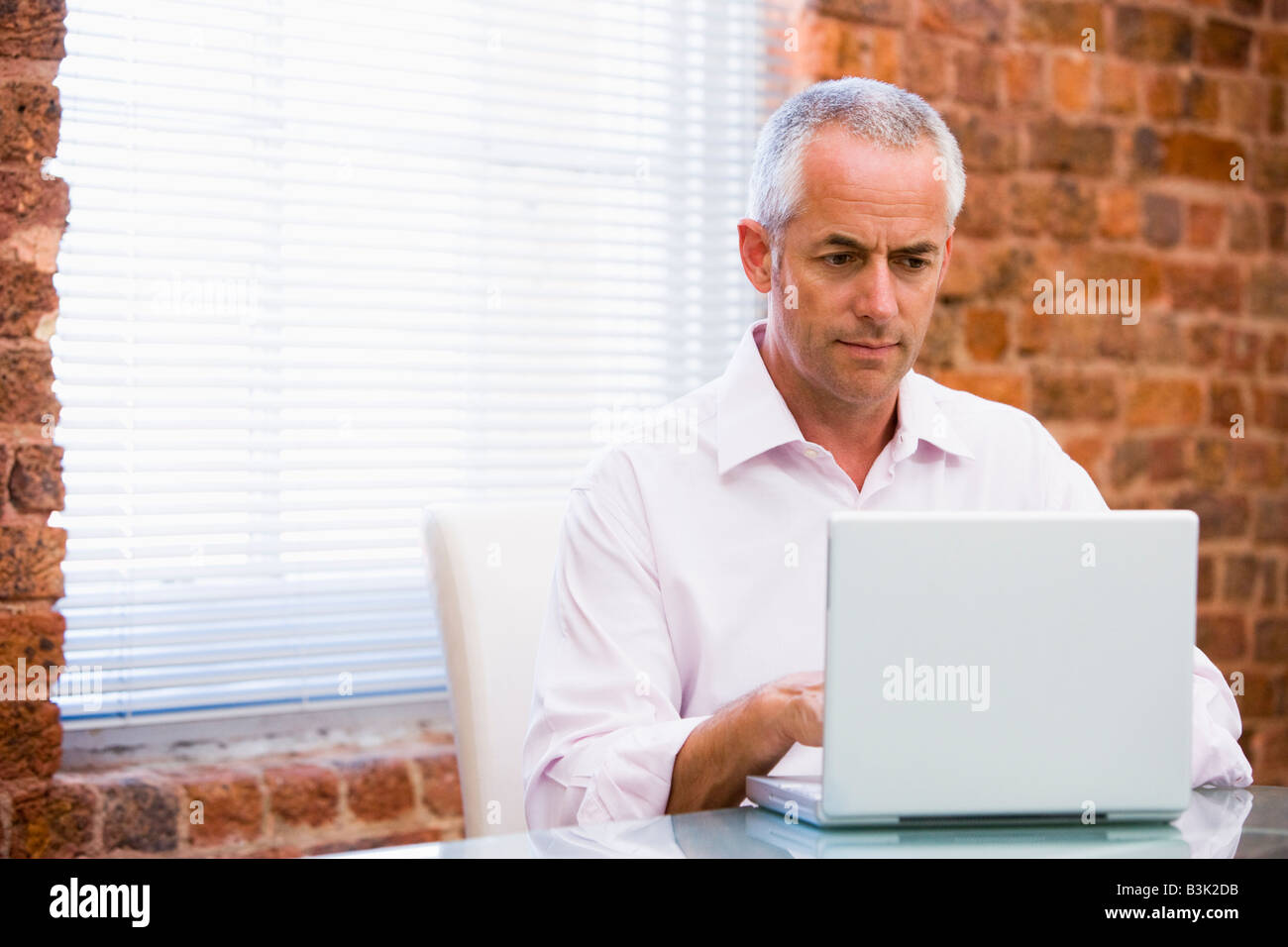 Businessman in office looking at laptop Stock Photo