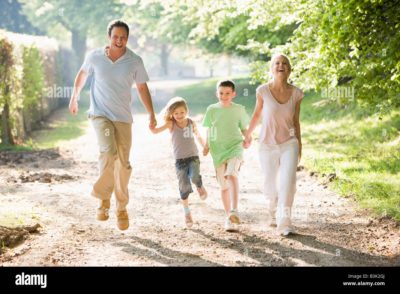 Family running outdoors holding hands and smiling Stock Photo