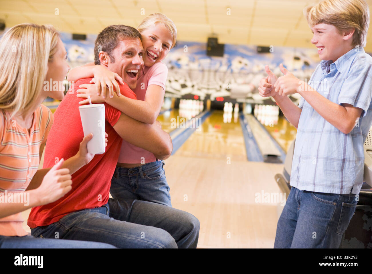 Family in bowling alley cheering and smiling Stock Photo