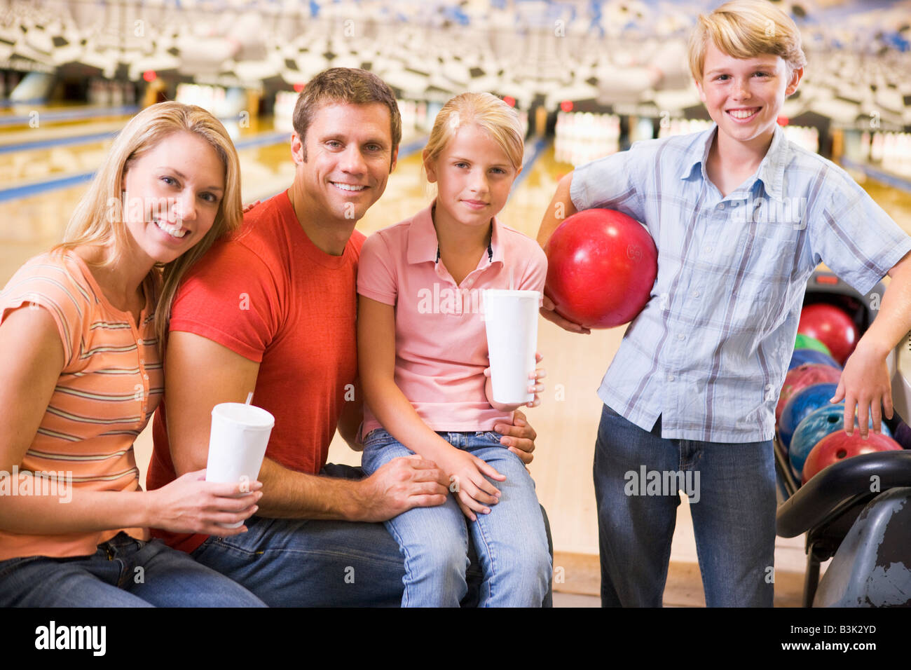 Family in bowling alley with drinks smiling Stock Photo