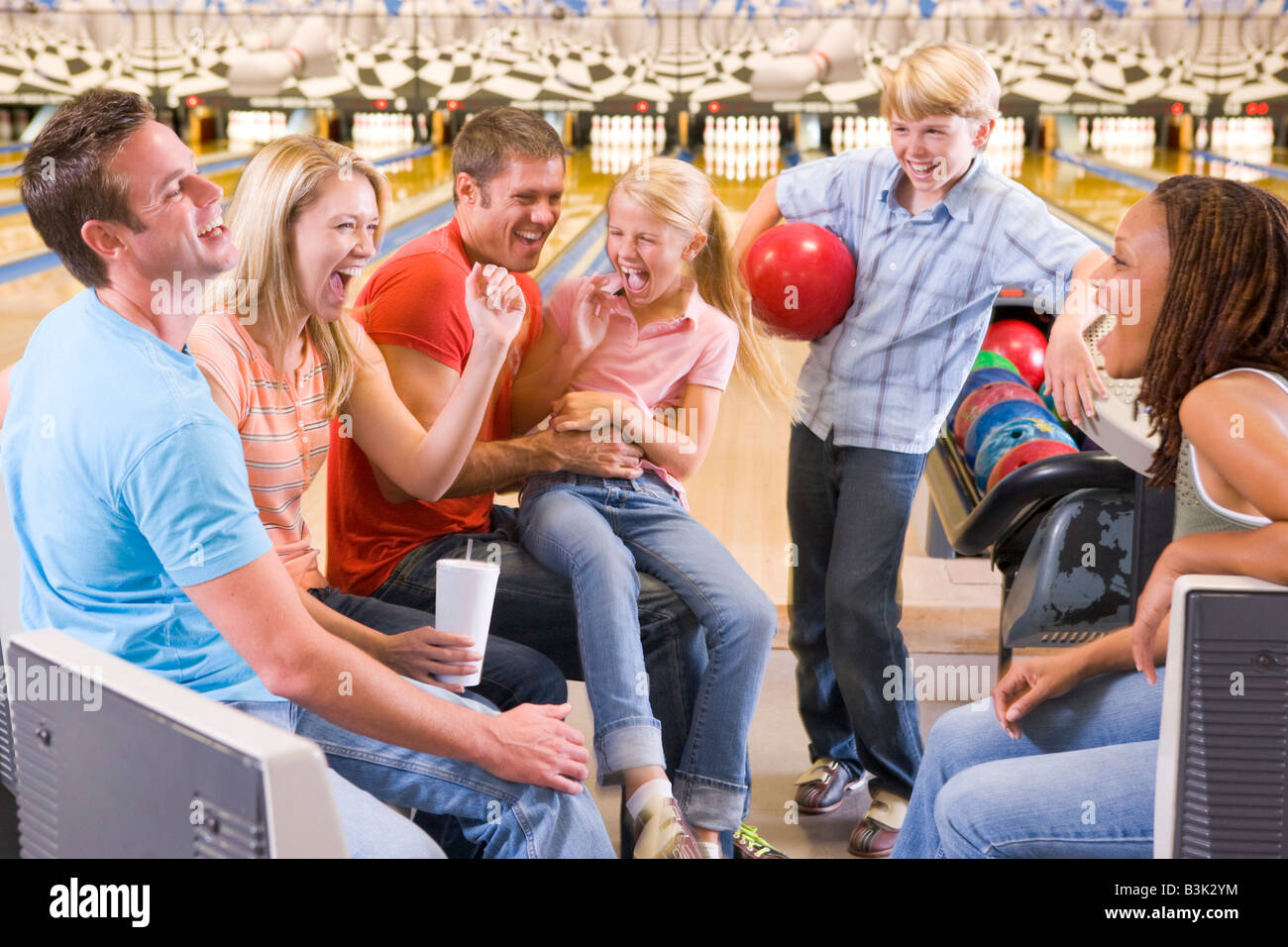 Family in bowling alley with two friends cheering and smiling Stock Photo
