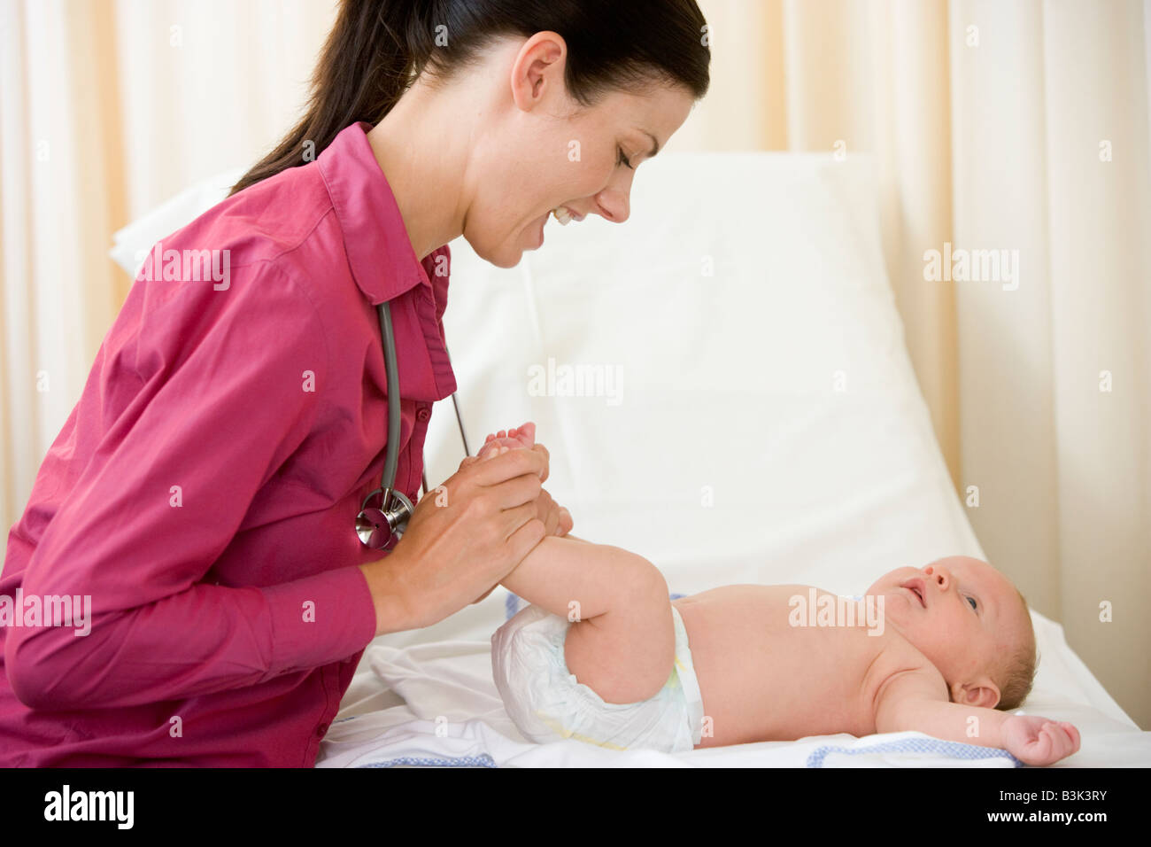 Doctor giving checkup to baby in exam room smiling Stock Photo