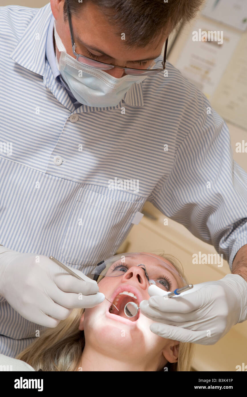 Dentist in exam room with woman in chair Stock Photo