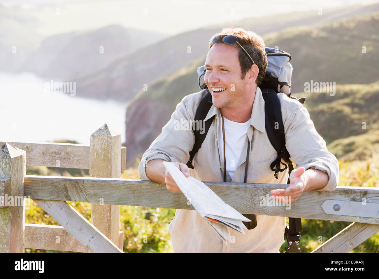 Man relaxing on cliffside path holding map and laughing Stock Photo