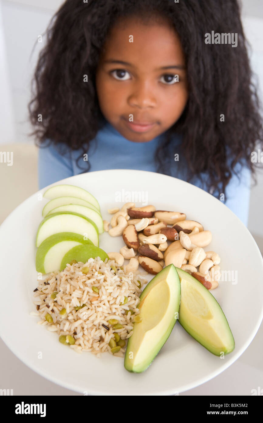 Young girl in kitchen eating rice fruit and nuts Stock Photo Alamy