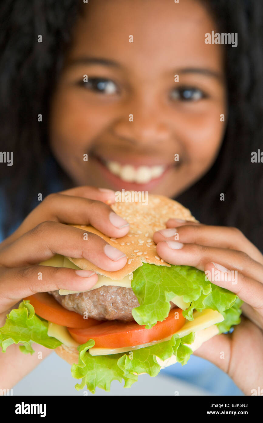 Young girl eating cheeseburger smiling Stock Photo Alamy