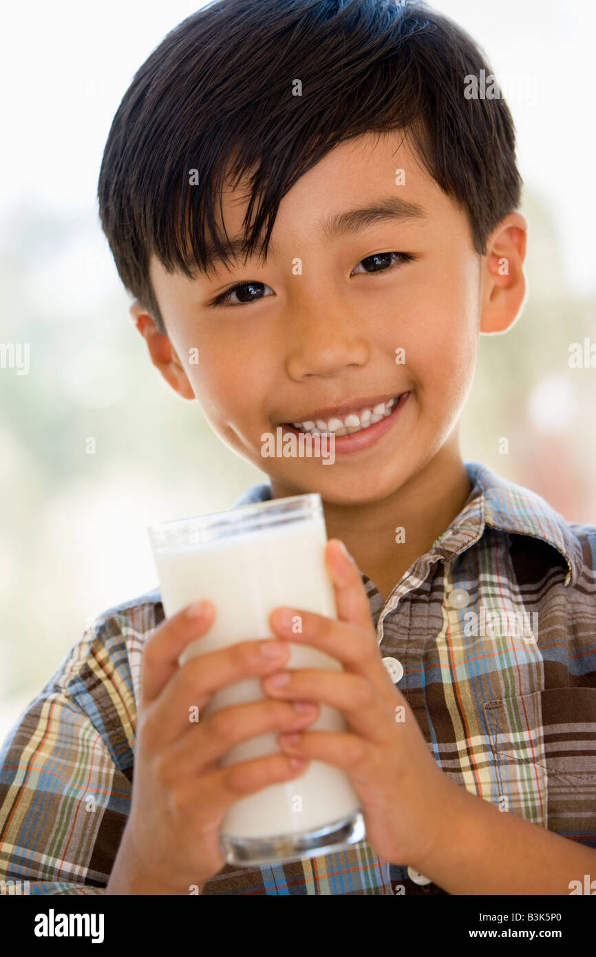 Young boy indoors drinking milk smiling Stock Photo