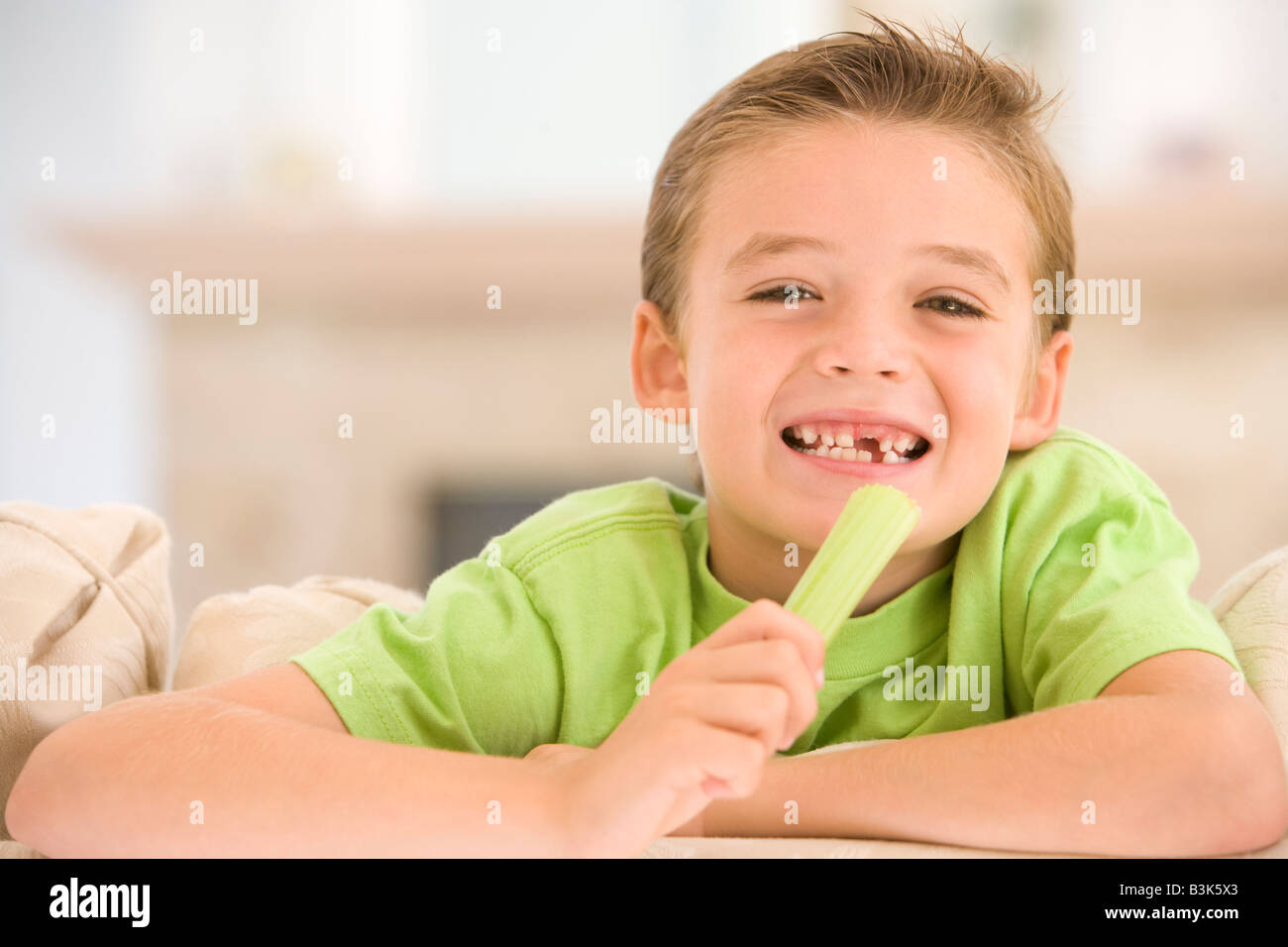 Young boy eating celery in living room smiling Stock Photo Alamy