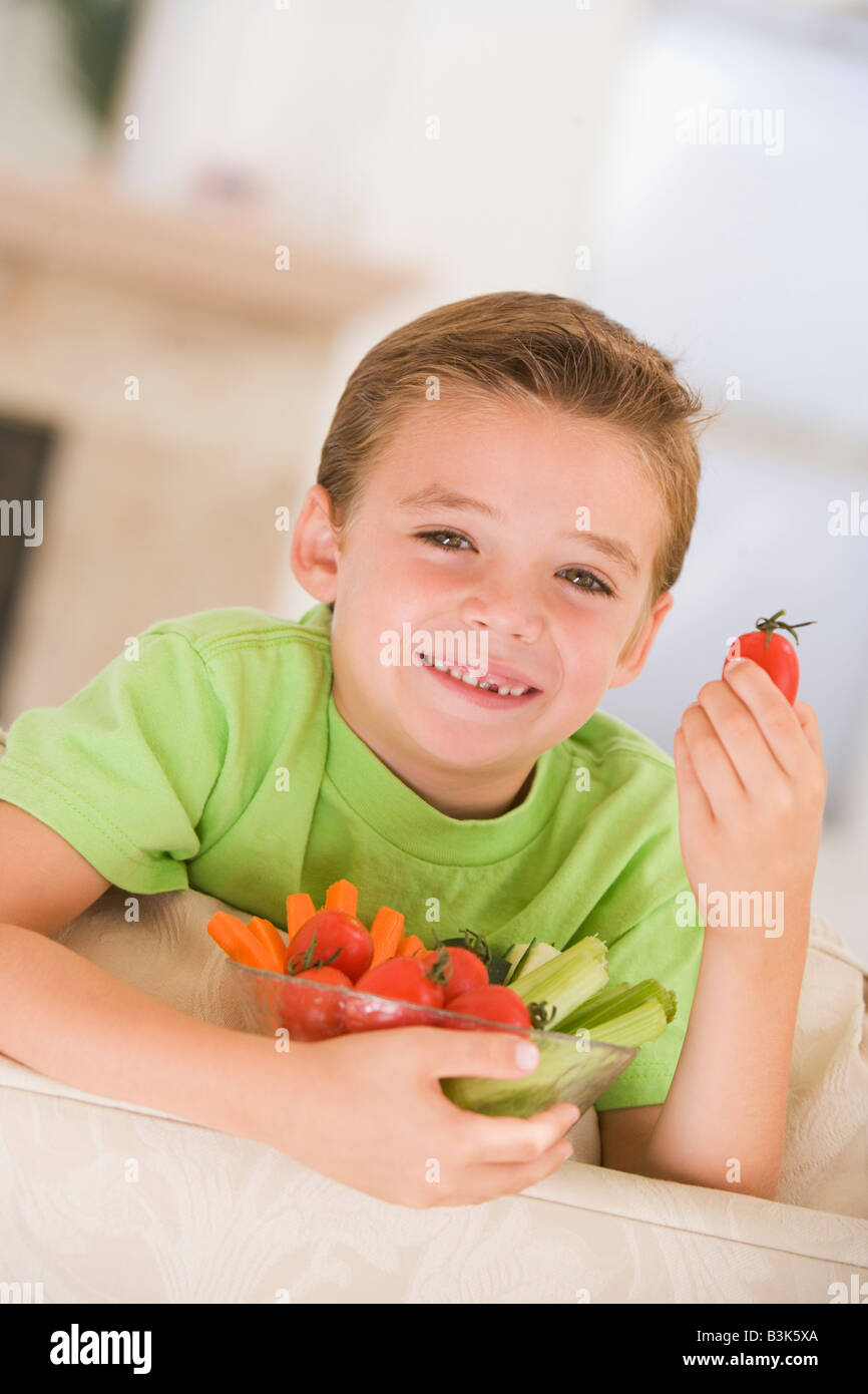 Young boy eating bowl of vegetables in living room smiling Stock Photo ...