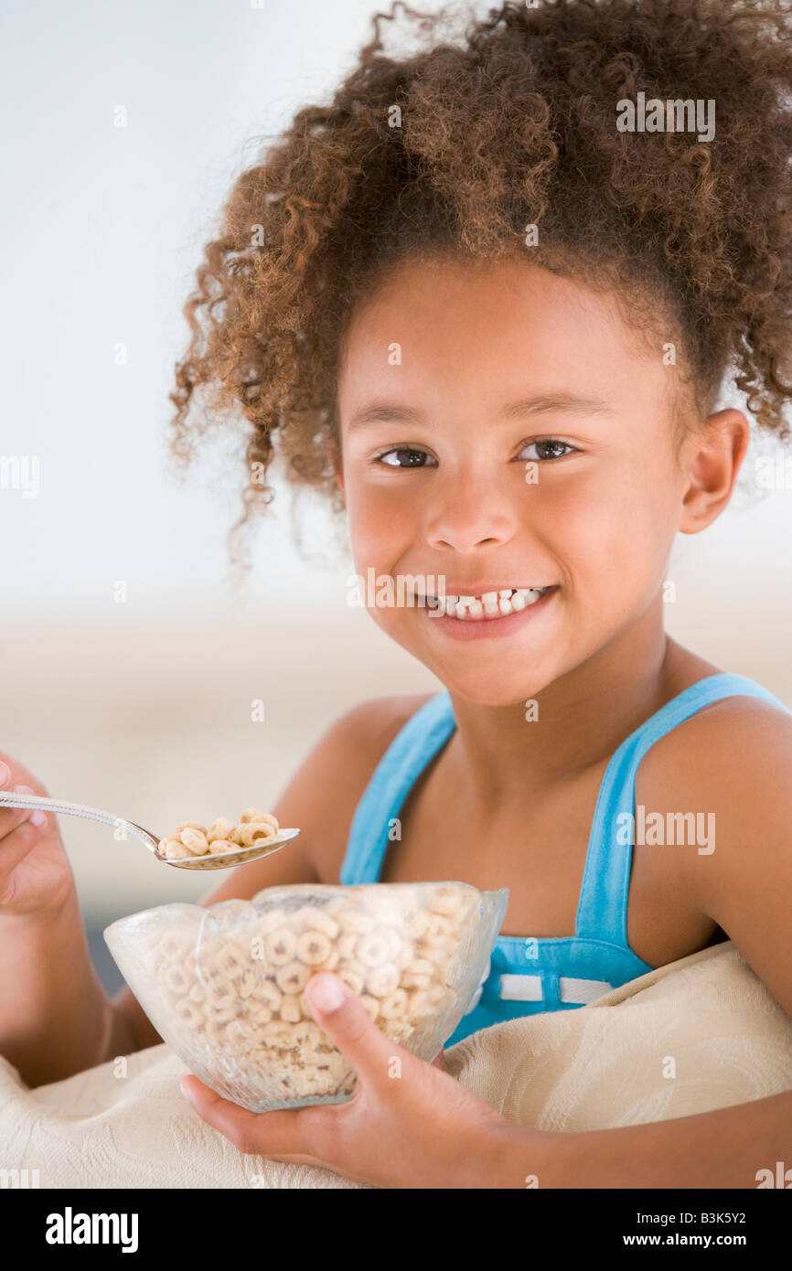 Young girl eating cereal in living room smiling Stock Photo Alamy