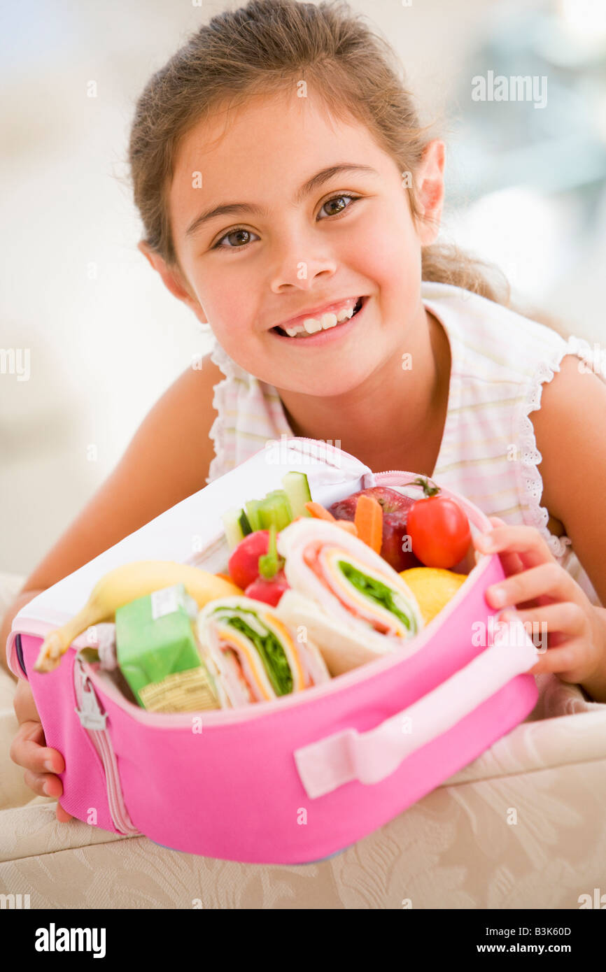 Young girl holding packed lunch in living room smiling Stock Photo Alamy