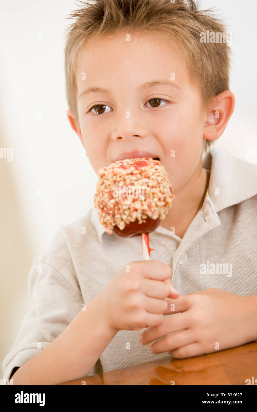 Young boy indoors eating candy apple Stock Photo