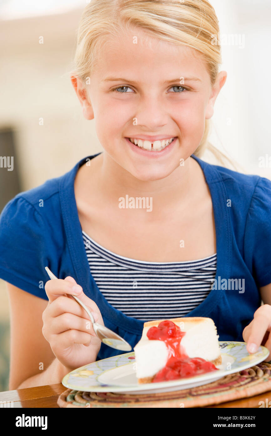 Young girl indoors eating cheesecake smiling Stock Photo Alamy