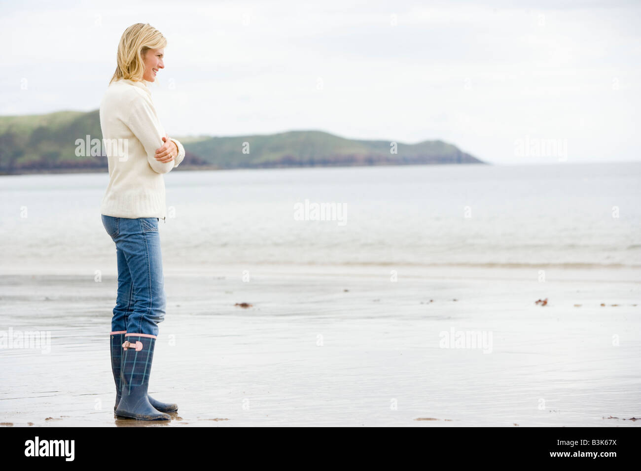 Woman standing on beach smiling Stock Photo - Alamy