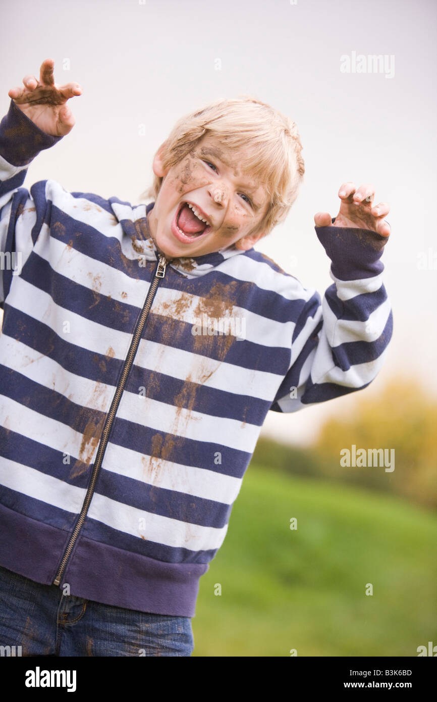 Young boy standing outdoors dirty and smiling Stock Photo