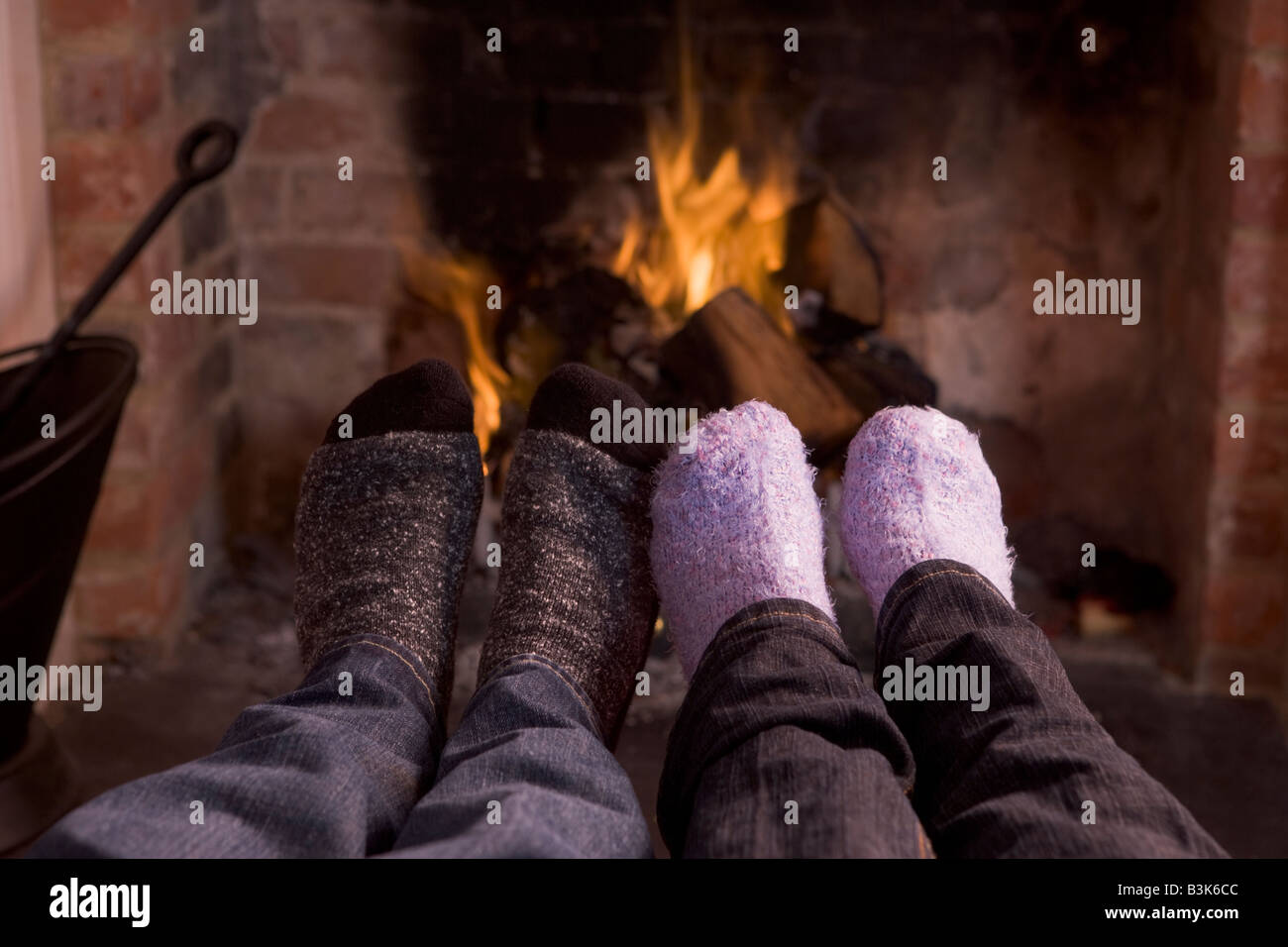 Couple's feet warming at a fireplace Stock Photo