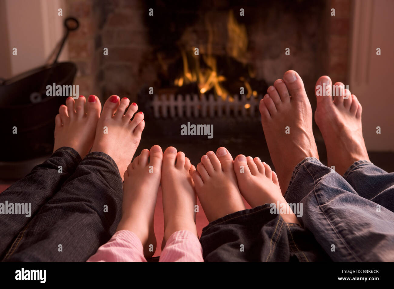 Family of feet warming at a fireplace Stock Photo