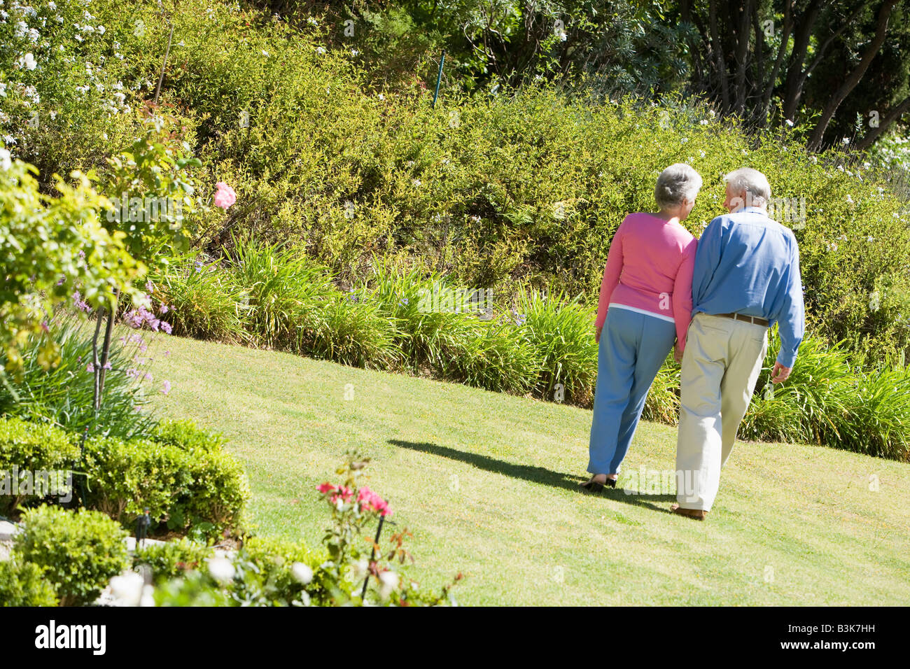 Senior couple walking through a flower garden Stock Photo - Alamy