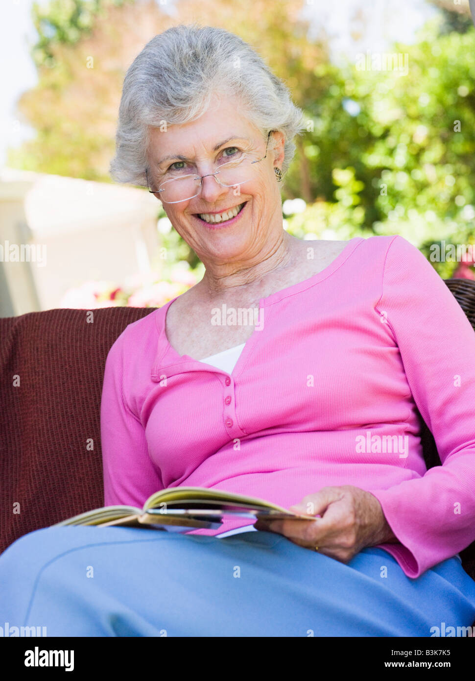 Senior woman sitting outdoors on a chair reading a book Stock Photo Alamy