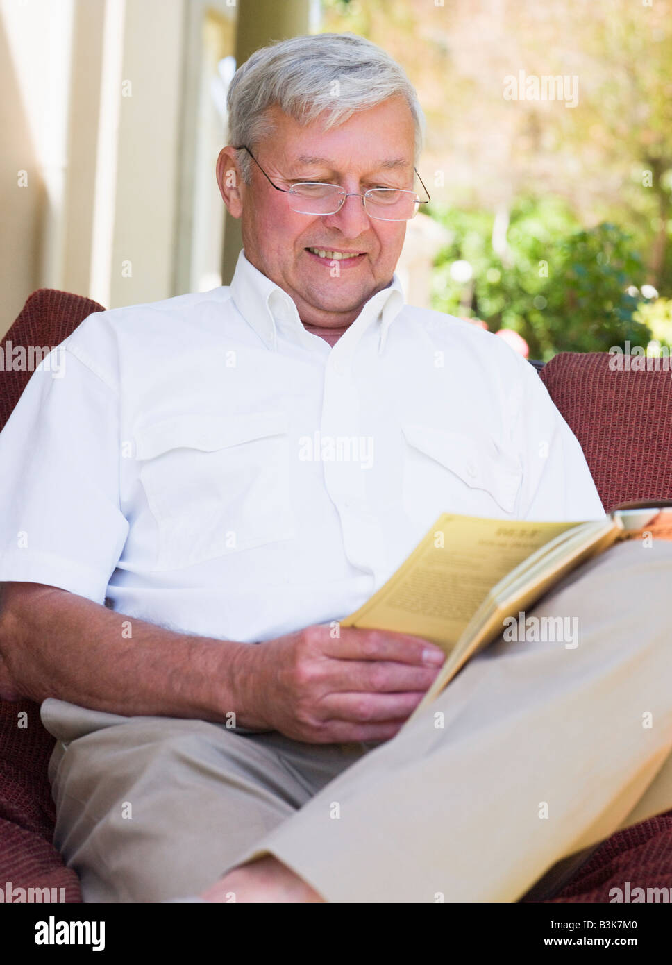 Senior woman sitting outdoors on a chair reading a book Stock Photo - Alamy