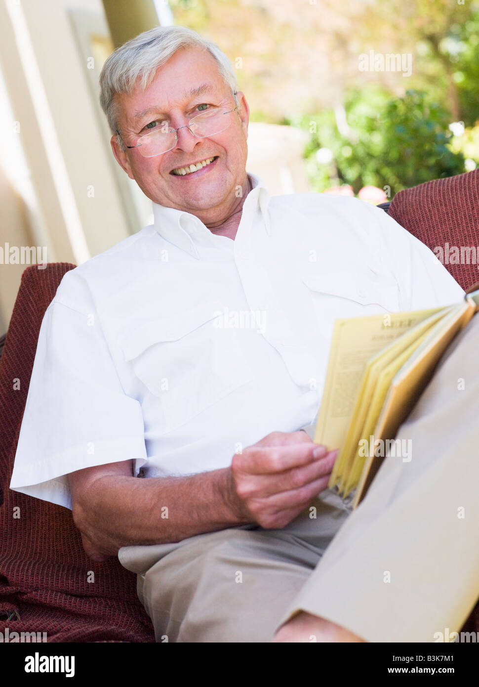 Senior woman sitting outdoors on a chair reading a book Stock Photo - Alamy
