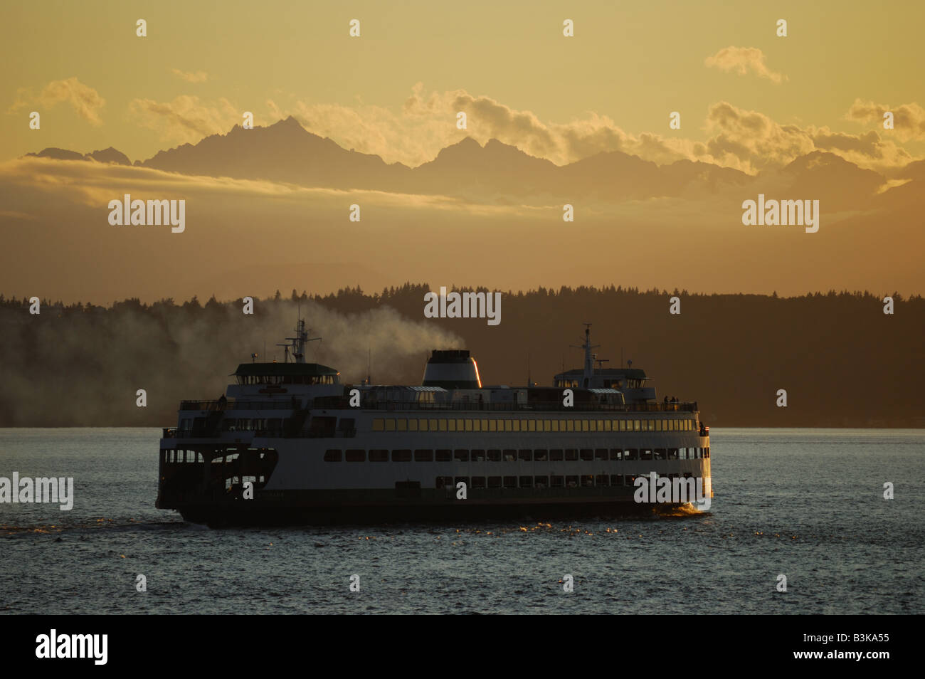 A Washington State ferry leaves Edmonds, WA for Kingston, WA. The Olympic Mtns. are seen in the background. Stock Photo