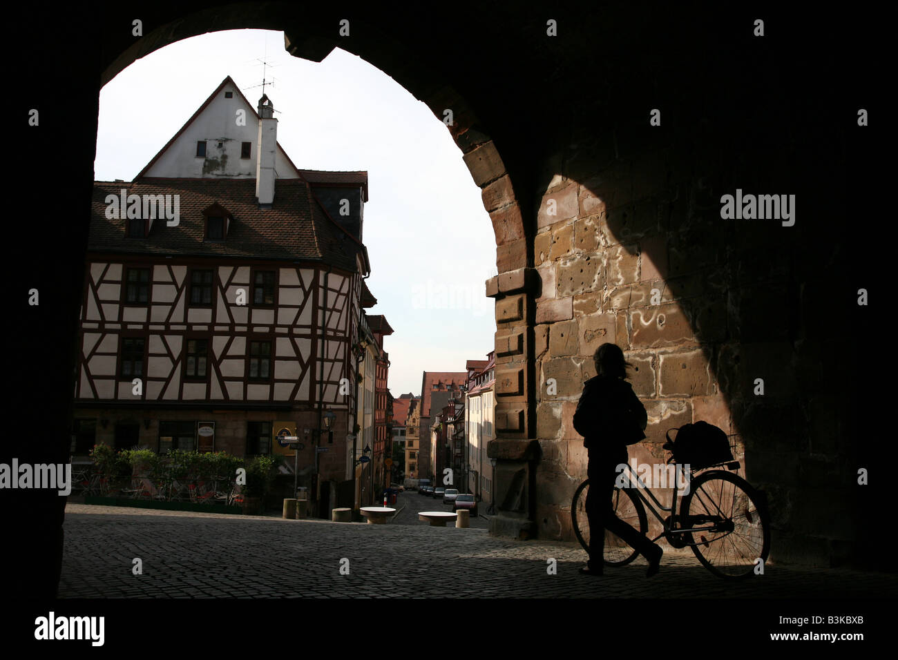 Silhouetted cyclist walking through the medieval Tiergartnertor gate to Albrecht Durer's House in Nuremberg, Germany Stock Photo