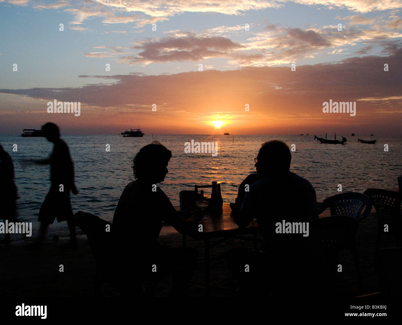 couple sat silhouetted on the beach watching the sunset Stock Photo - Alamy
